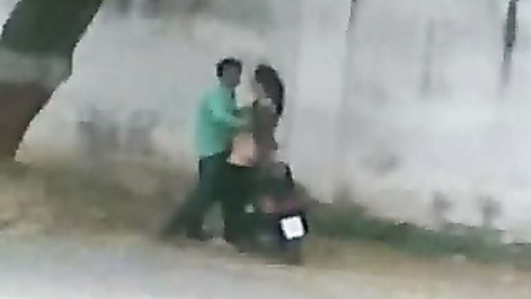 Pakistani couple bangs on a moped by the side of the road