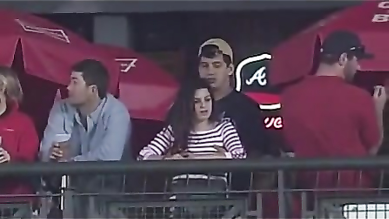 Fondling his cute girlfriend at a baseball game